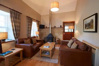 a living room with leather furniture and a fireplace at Home Farm Cottages, Glendaruel, Argyll. Scotland in Clachan of Glendaruel
