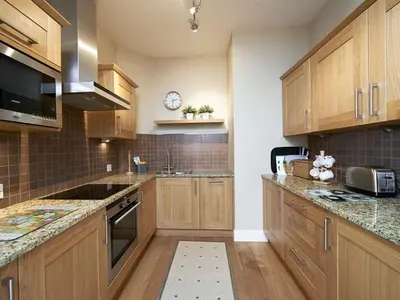a kitchen with wooden cabinets and a clock on the wall at Home Farm Cottages, Glendaruel, Argyll. Scotland in Clachan of Glendaruel