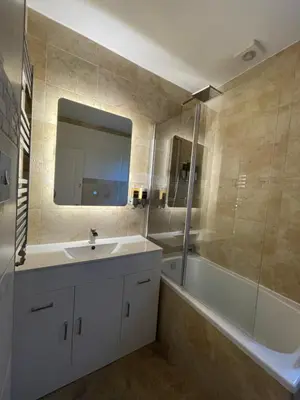 a bathroom with a sink and a tub and a mirror at Windsor House in Falkirk