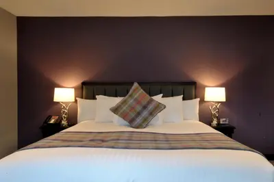 a bedroom with a large white bed with two lamps at The Beach House Loch Lomond in Luss