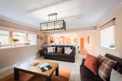 a living room with a couch and a table at The Old Byre with Hot Tub in Forgandenny