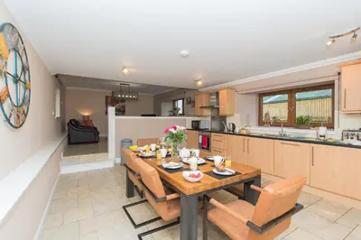 a kitchen and dining room with a wooden table and chairs at The Old Byre with Hot Tub in Forgandenny