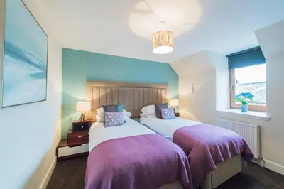 two beds in a bedroom with purple blankets at The Old Byre with Hot Tub in Forgandenny