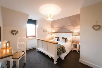 a bedroom with a white bed and a window at The Old Byre with Hot Tub in Forgandenny