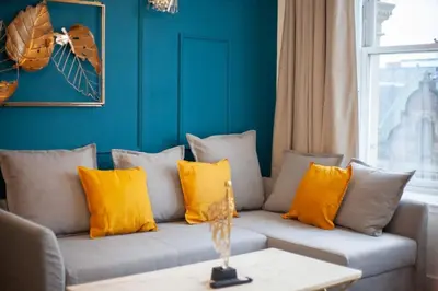 a living room with a couch with yellow pillows at Stunning One bed with parking in City Centre in Glasgow