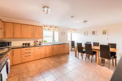 a kitchen with wooden cabinets and a table and chairs at Keepers Lodge with Hot Tub in Forgandenny