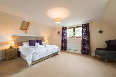 a bedroom with a bed and a window and a chair at The Granary with Hot Tub in Forgandenny
