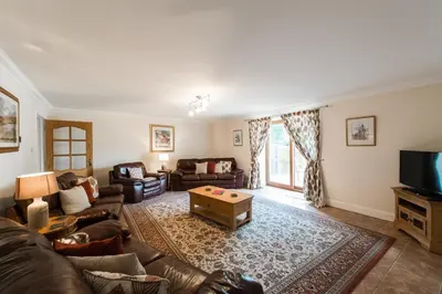 a living room with a couch and a tv at The Granary with Hot Tub in Forgandenny