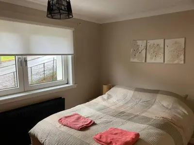 a bedroom with a bed with two pink towels on it at Budget friendly apartment with stairs Near Glasgow airport and Loch Lomond in Clydebank