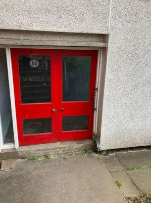 a red door in the side of a building at Budget friendly apartment with stairs Near Glasgow airport and Loch Lomond in Clydebank
