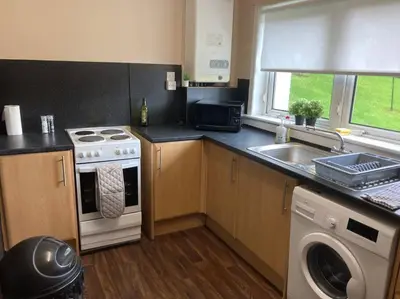a kitchen with a stove and a sink and a dishwasher at Budget friendly apartment with stairs Near Glasgow airport and Loch Lomond in Clydebank