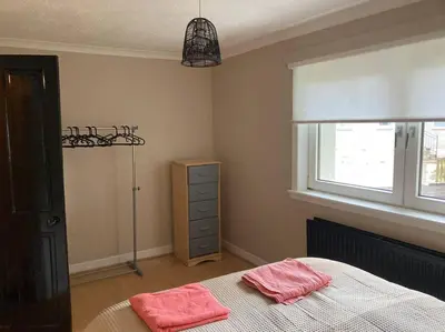 a bedroom with a bed with two pink towels on it at Budget friendly apartment with stairs Near Glasgow airport and Loch Lomond in Clydebank