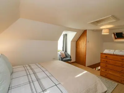 a bedroom with a bed and a dresser and a chair at The Coach House in Oban