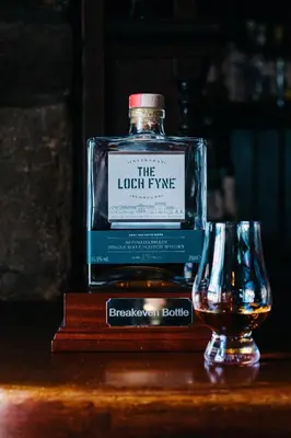 a bottle of whisky sitting next to a glass at The George Hotel in Inveraray