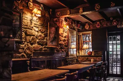a bar with wooden tables and a stone wall at The George Hotel in Inveraray