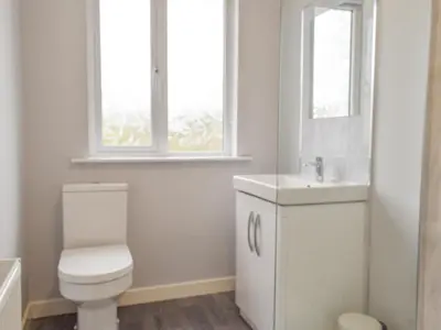 a white bathroom with a toilet and a sink at The Shieling in Biggar