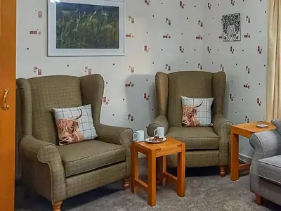 a living room with two chairs and a table at The Shieling in Biggar