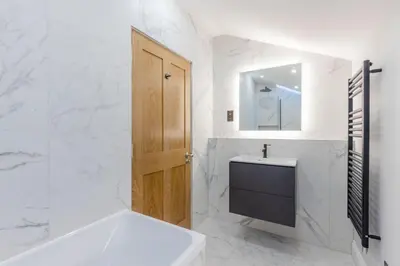 a bathroom with a sink and a wooden door at Dragon Suites - Yukina Suite - 2 bed city centre house with garden in Edinburgh