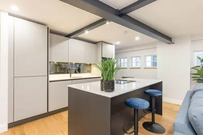 a kitchen with white cabinets and a island with stools at Dragon Suites - Yukina Suite - 2 bed city centre house with garden in Edinburgh