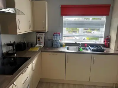 a kitchen with white cabinets and a sink and a window at 5 minutes to Glasgow airport in Paisley