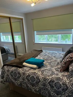 a bedroom with a bed with blue pillows and a mirror at 5 minutes to Glasgow airport in Paisley