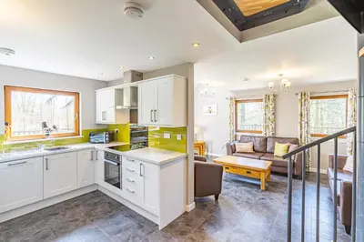 a kitchen with white cabinets and a living room at Lord Galloway 31 with Hot Tub in Newton Stewart