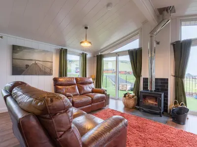 a living room with a leather couch and a fireplace at Chalet Loch Leven Lodge 25 East by Interhome in Kinross