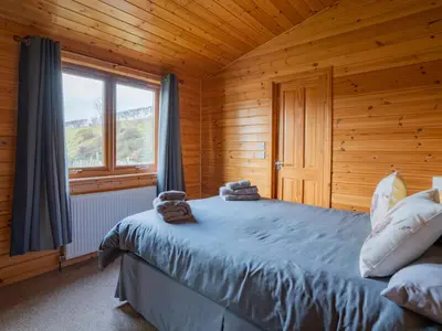 a bedroom with a bed in a wooden cabin at Chalet Loch Leven Lodge 10 by Interhome in Kinross