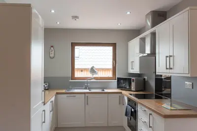 a kitchen with white cabinets and a sink and a window at Lord Galloway 33 with Hot Tub in Newton Stewart