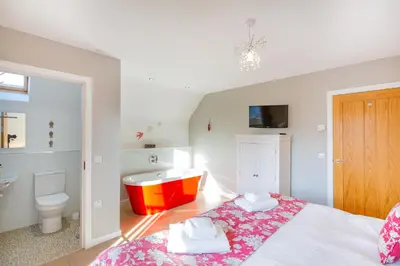 a bedroom with a bed and a tub and a sink at Lord Galloway 34 with Hot Tub in Newton Stewart
