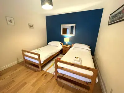 two beds in a room with a blue wall at Beautiful Rural 3BR Cottage with Stunning Views - Pass the Keys in Auldgirth