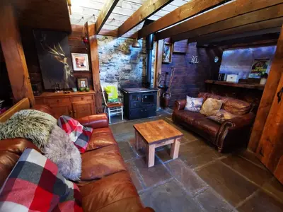 a living room with leather couches and a wood stove at Ranch House in Newton Stewart