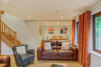 a living room with a leather couch and a chair at Lord Galloway 36 with Hot Tub in Newton Stewart