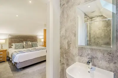 a bedroom with a bed and a sink and a mirror at Lord Galloway 36 with Hot Tub in Newton Stewart