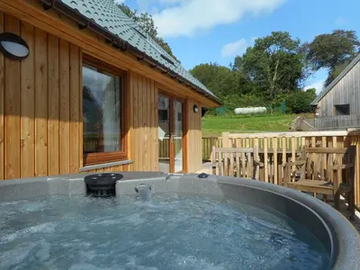 a hot tub in front of a wooden house at Lord Galloway 36 with Hot Tub in Newton Stewart