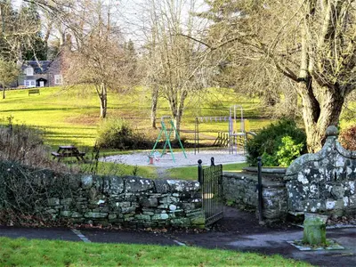 a park with a stone fence and a playground at Greenbrae East in Crieff