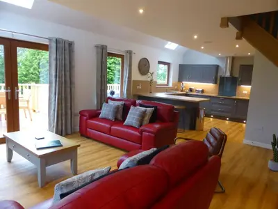 a living room with red couches and a kitchen at Lord Galloway 37 with Hot Tub in Newton Stewart