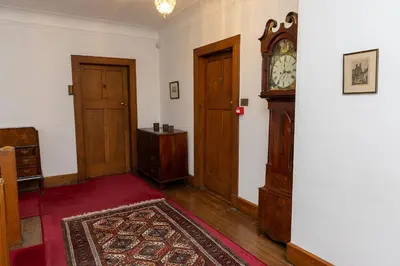 a room with a clock on the wall next to two doors at Newholme House in Stirling