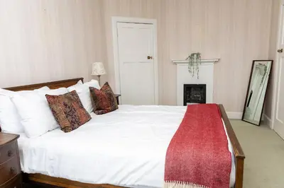 a bedroom with a white bed and a fireplace at Newholme House in Stirling