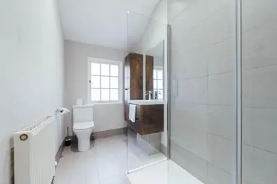 a white bathroom with a shower and a toilet at Newholme House in Stirling