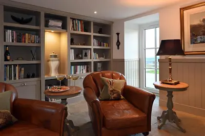 a living room with two chairs and a table and book shelves at Kipney Farmhouse with hot tub in Perth
