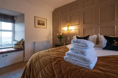 a bedroom with a bed with a pile of towels on it at Kipney Farmhouse with hot tub in Perth