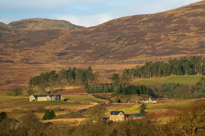 a farm in a field with mountains in the background at Lapwing - Stylish one bedroom country steading in Perth