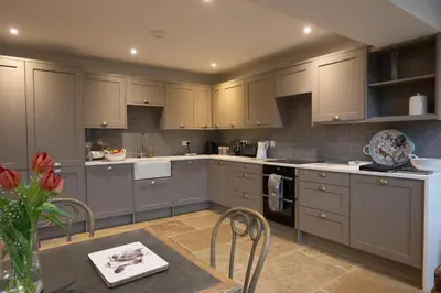 a kitchen with gray cabinets and a table with a vase of flowers at Lapwing - Stylish one bedroom country steading in Perth