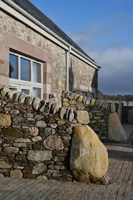 a stone wall with two large rocks in front of a building at Oystercatcher - Converted luxury steading in Perth