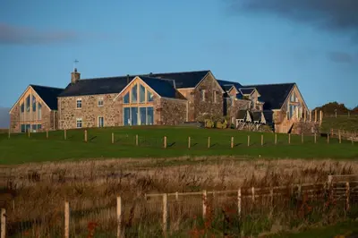 a large stone house in a field with a fence at Oystercatcher - Converted luxury steading in Perth