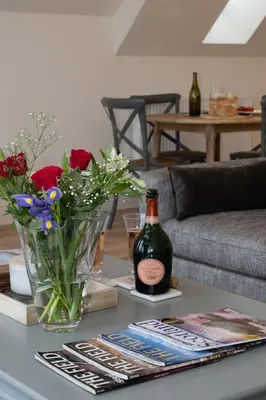 a table with a bottle of wine and flowers on it at Capercaillie Cottage - Luxury converted steading in Perth