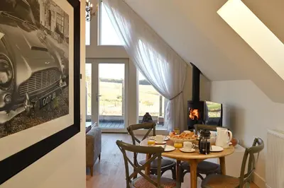 a dining room with a table with chairs and a fireplace at Capercaillie Cottage - Luxury converted steading in Perth