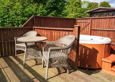 two chairs and a table on a deck with a hot tub at Bluebell Lodge 4 with Hot Tub in Newton Stewart