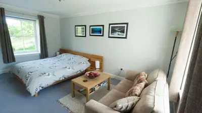 a living room with a bed and a couch at The Byre in Strathyre